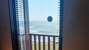 An open door leading to a balcony with a view of the sea.