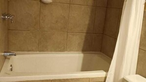 A bathroom with a bathtub, toilet, and shower curtain.