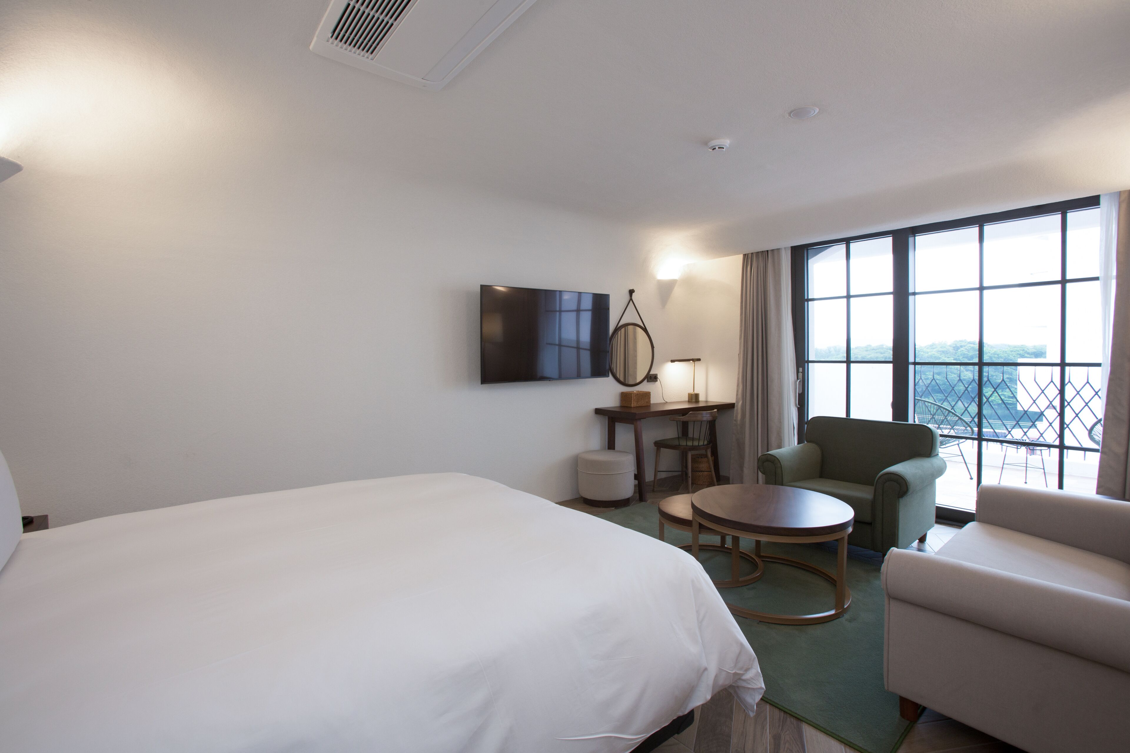 Une chambre d’hôtel avec un grand lit, un bureau avec une chaise, un canapé et une vue sur la ville.