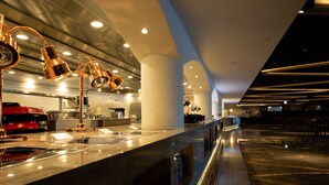 Een moderne hotellobby met een marmeren receptiebalie, gouden hanglampen en een ruime zithoek.