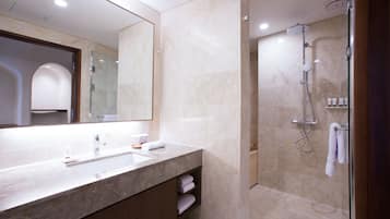 A modern bathroom with a marble vanity, a large mirror, and a glass-enclosed shower area.