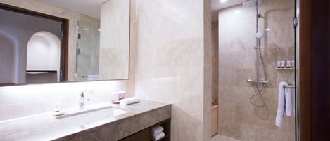 Une salle de bain moderne avec un meuble-lavabo en marbre, un grand miroir et une douche séparée par des parois en verre.