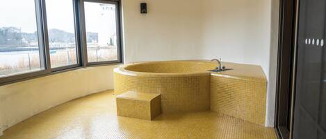 A bathroom with a large bathtub, a window, and a tiled floor.