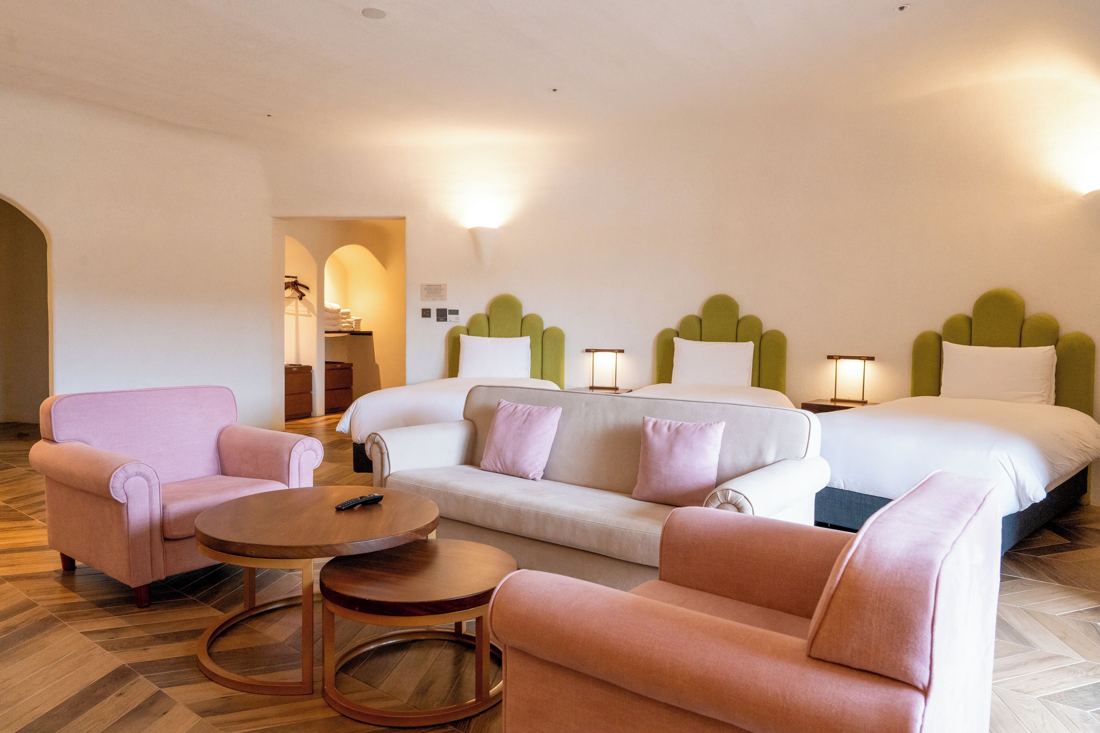 A hotel room with a bed, two sofas, a round table, and a chair.