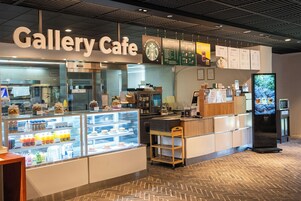 Interior de una cafetería con una vitrina, pizarras con el menú y una pantalla digital.