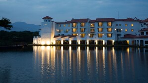 Een groot, meerhoog hotel met een opvallende toren, weerspiegeld in een kalm wateroppervlak.