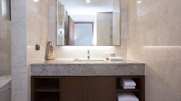 A modern bathroom with a marble sink, wooden cabinets, and a large mirror.