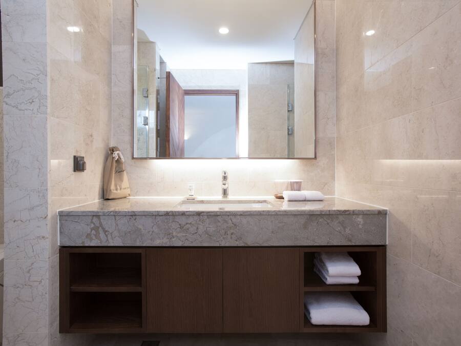 A modern bathroom with a marble sink, wooden cabinets, and a large mirror.
