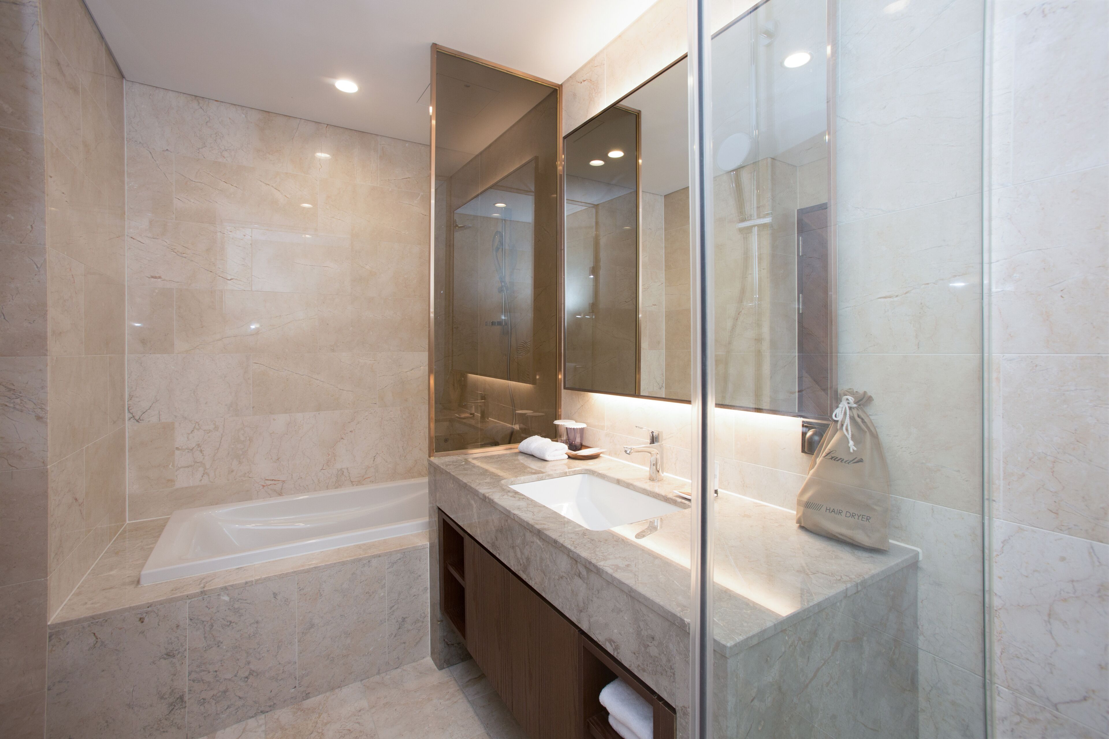 A modern bathroom with a large mirror, a bathtub, and a sink.