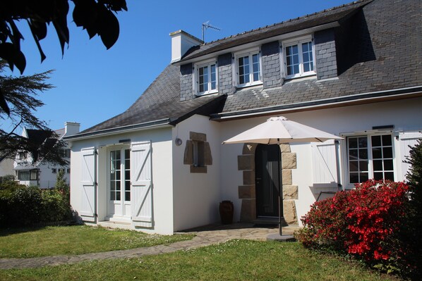 A two-story house with a stone facade, a large front door, and a small porch area.