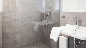 Une salle de bain moderne avec une douche à parois de verre, un lavabo blanc et un grand miroir.