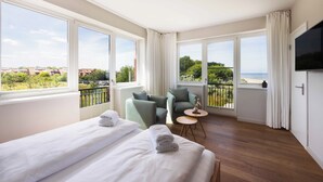 A hotel room with two beds, a balcony with a view, a TV, and a small table.