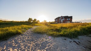 A sandy path leading to a brick house with a clear sky.