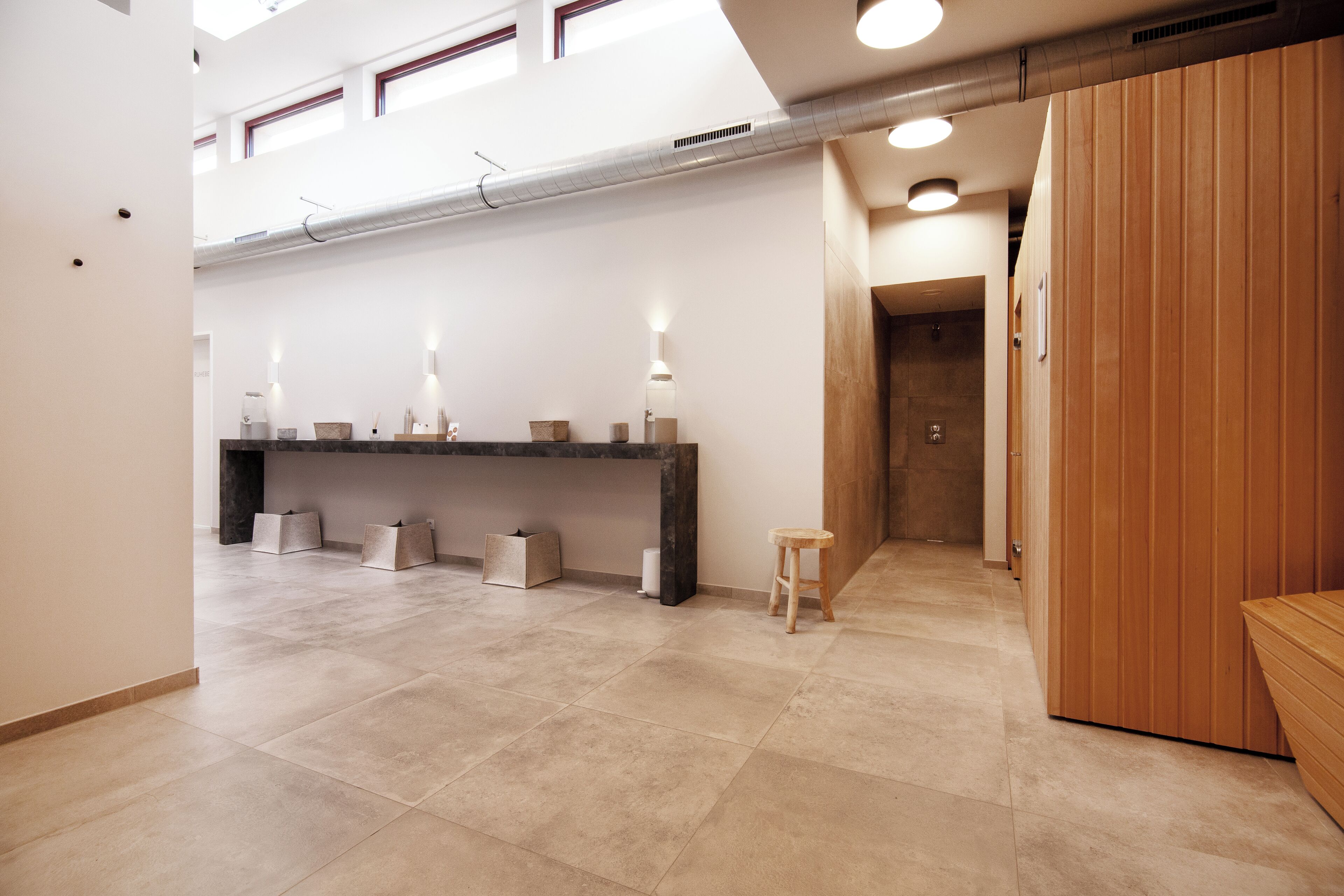 Ein modernes Interieur mit einer Rezeption, einer Holzbank und einem Fliesenboden.