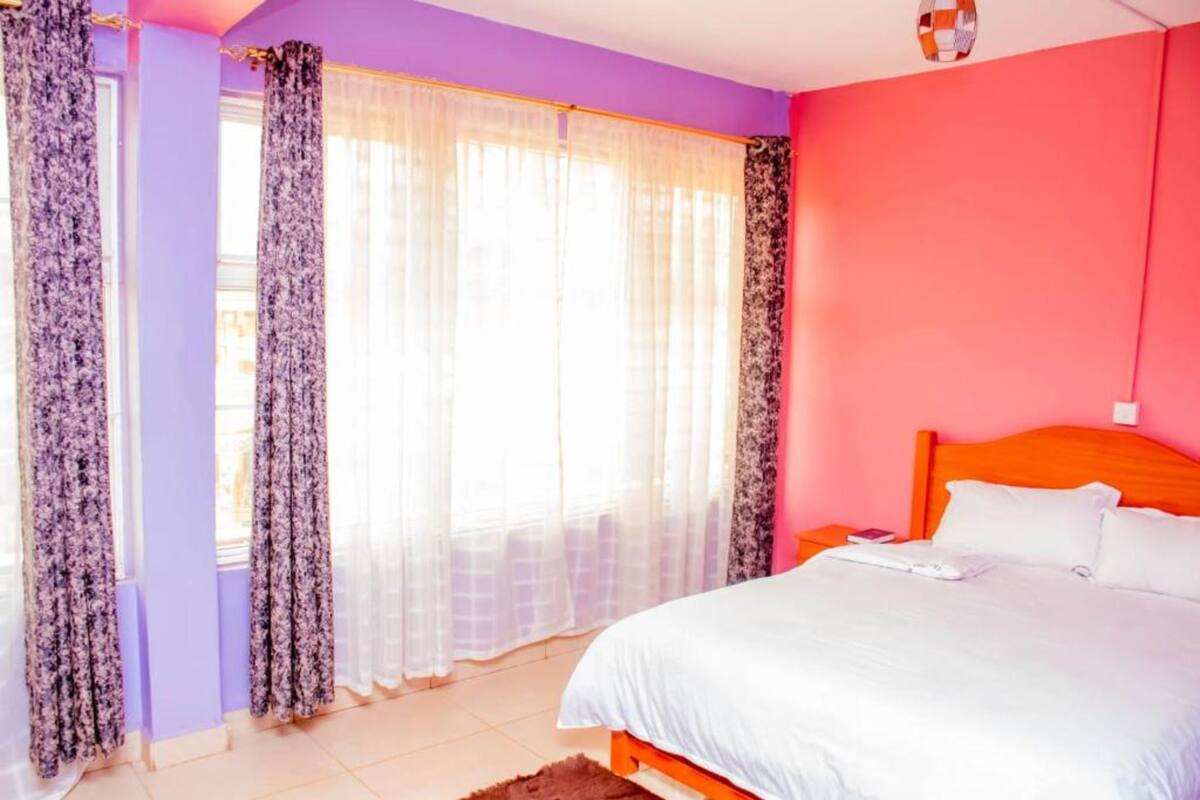 A bedroom with a bed, curtains, and a window.