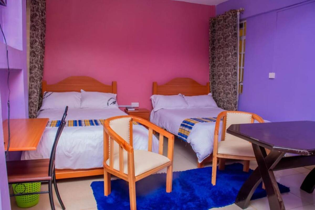 A room with two beds, a table, and a chair.