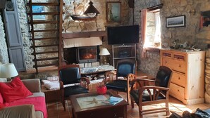 Ein gemütliches Wohnzimmer mit Steinwänden, einem Kamin, einem Fernseher und Holzmöbeln.