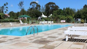 Une piscine dotée de chaises longues et d’un espace ombragé.