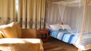 Une chambre à coucher comprenant un lit, une chaise, une table de chevet et une fenêtre avec des rideaux.
