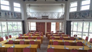 Une salle de conférence dotée de plusieurs tables et chaises, de grandes fenêtres et d’œuvres d’art accrochées aux murs.