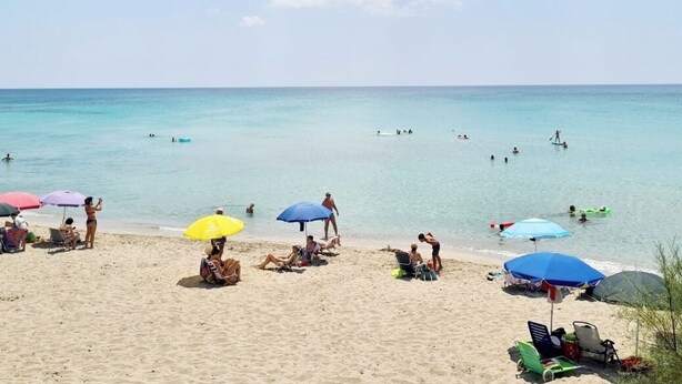 A beach with people sunbathing, swimming, and using umbrellas. - Villa AURORA, beautiful sea view! 400mt from the sandy beach. (Lizzano)