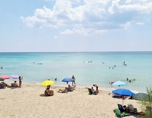 A beach with people sunbathing, swimming, and using umbrellas. - Villa AURORA, beautiful ocean view! 400 m from the sandy beach   (Lizzano)
