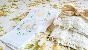 A neatly made bed with floral bedding, a lace pillow, and a decorative bow. - Villa AURORA, beautiful sea view! 400mt from the sandy beach. (Lizzano)