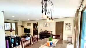 A spacious dining area with a long table, chairs, a piano, and a television. - CdA Hotspot - Hot Tub, Pool, & Sauna (Coeur d Alene)