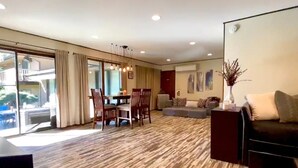A spacious living area with a dining table and chairs, a sofa, and a large window offering a view of the outdoors. - CdA Hotspot - Hot Tub, Pool, & Sauna (Coeur d Alene)