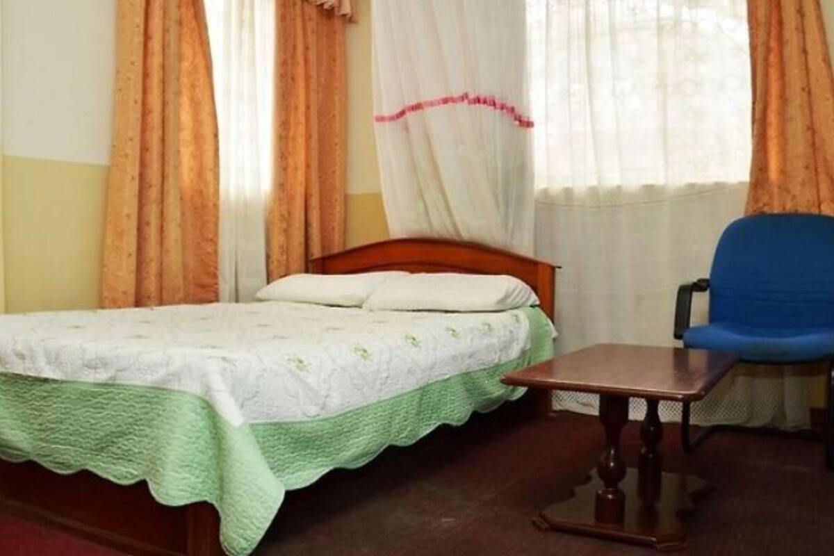 A room with a bed, a chair, and a window with curtains.