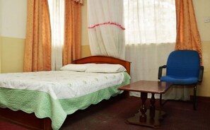 A room with a bed, a chair, and a window with curtains. - Hotel Green Garden (Nairobi)