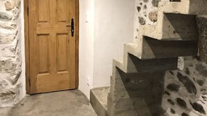 A stone staircase leading to a wooden door in a rustic interior. - Former "U FRAGNU" wine press (Omessa)