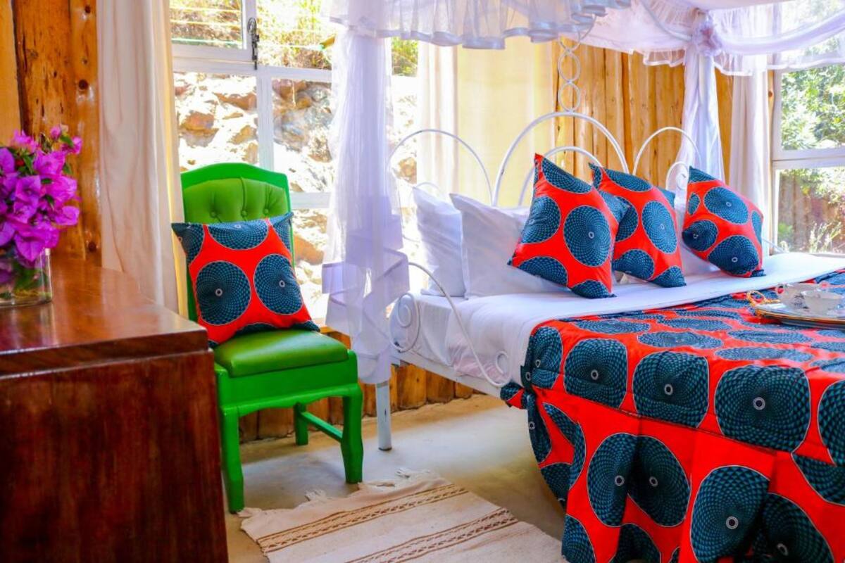 A bedroom with a bed, green chair, and a window with curtains.