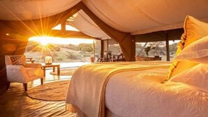 Una habitación acogedora y bien iluminada con una cama grande, una mesita y una silla.