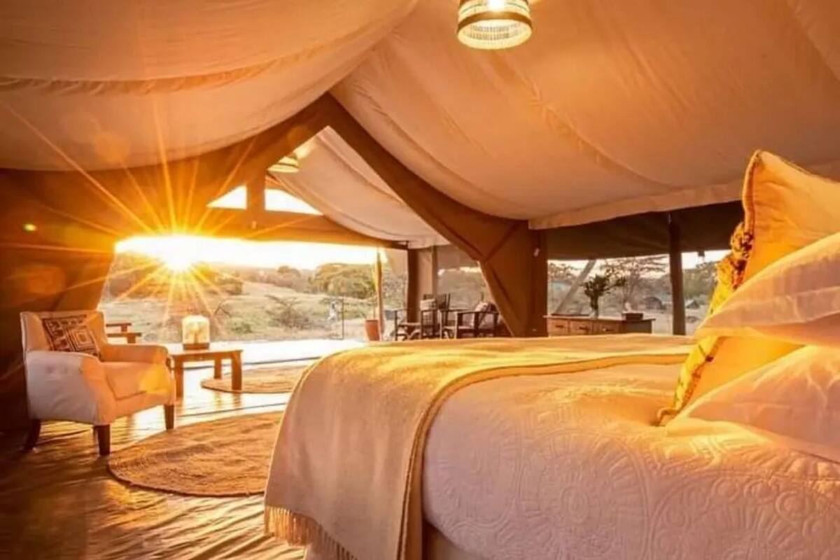 Una habitación acogedora y bien iluminada con una cama grande, una mesita y una silla.