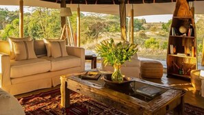 Alojamiento con carpa, un sofá, una mesa de centro, una estantería y vistas al exterior.
