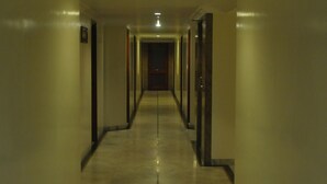 Un long couloir étroit, doté d’un sol et de murs en marbre, qui mène à une porte au bout.