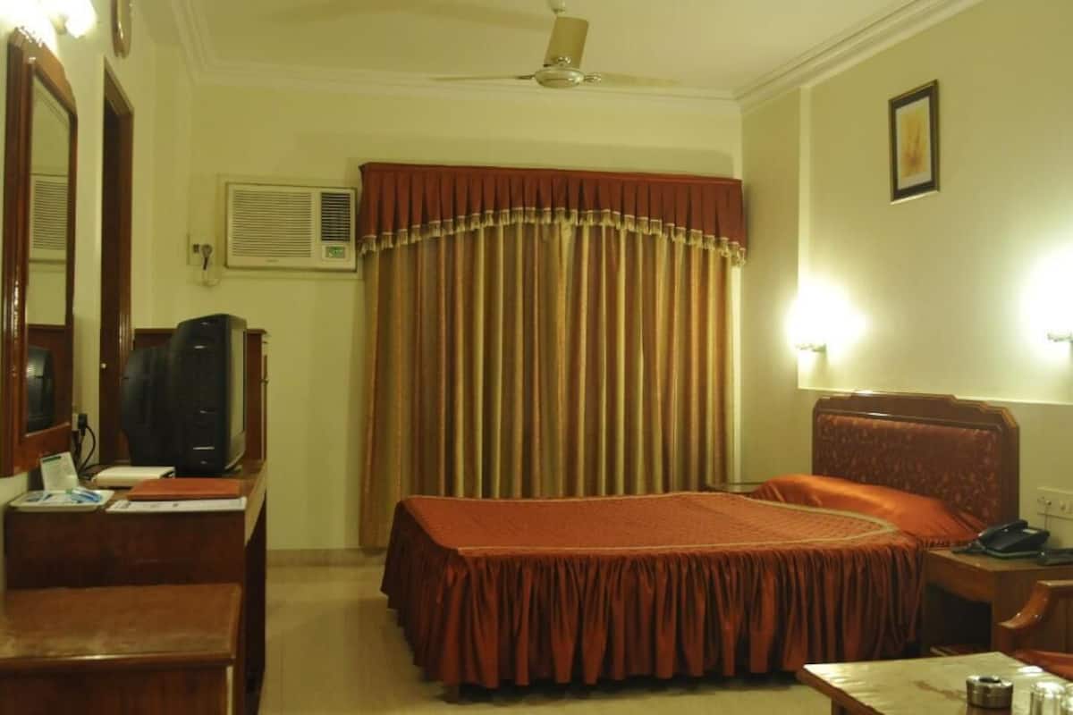 A hotel room with a bed, desk, chair, and a ceiling fan.