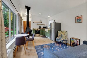 Een moderne keuken met een eethoek, een bank en uitzicht op een bos.
