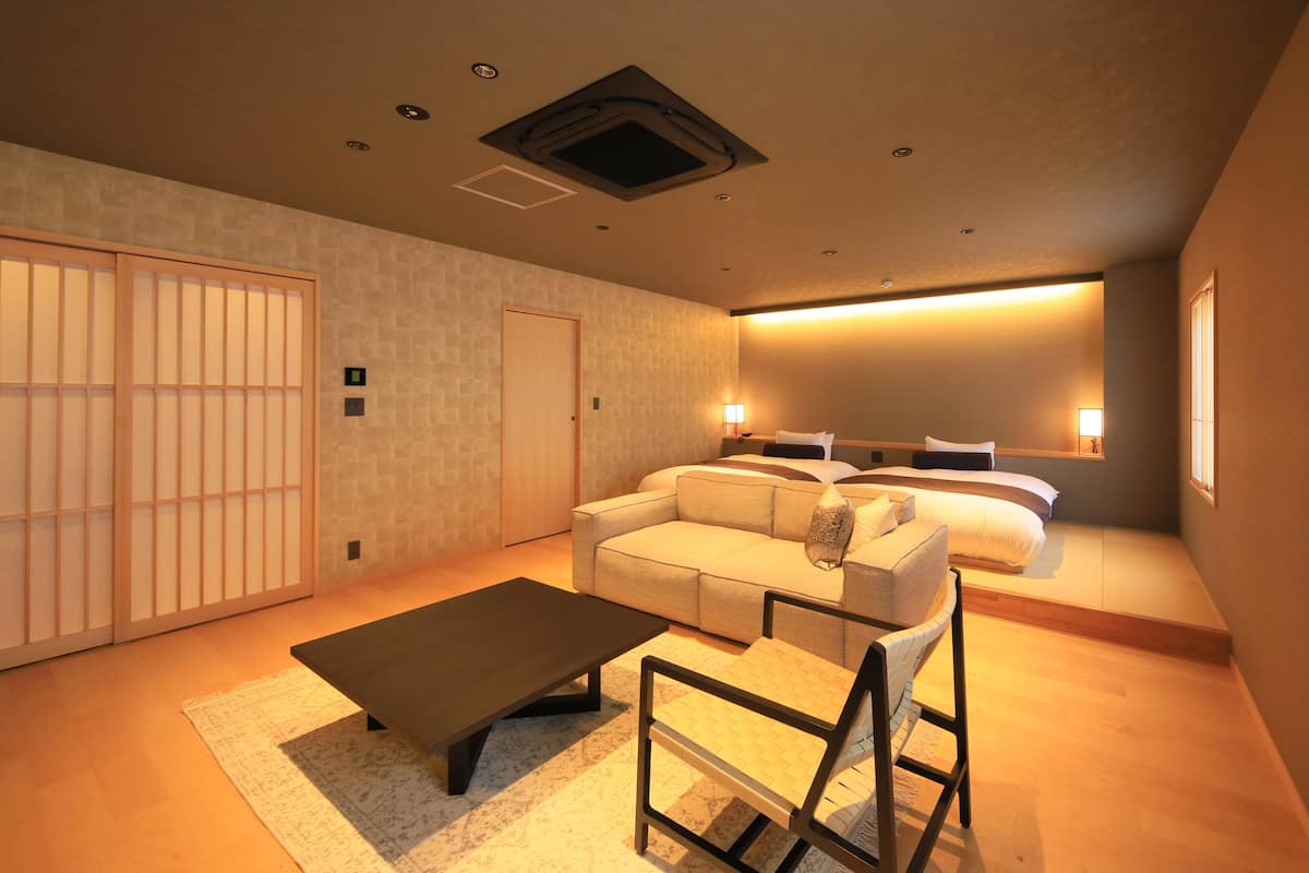 A modern hotel room with a sofa, a coffee table, a chair, and a bed.
