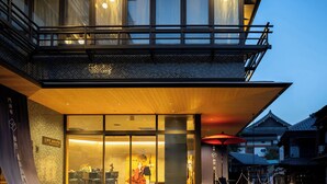Un edificio moderno con un amplio acceso de vidrio, un piso superior de madera y arquitectura tradicional al fondo.