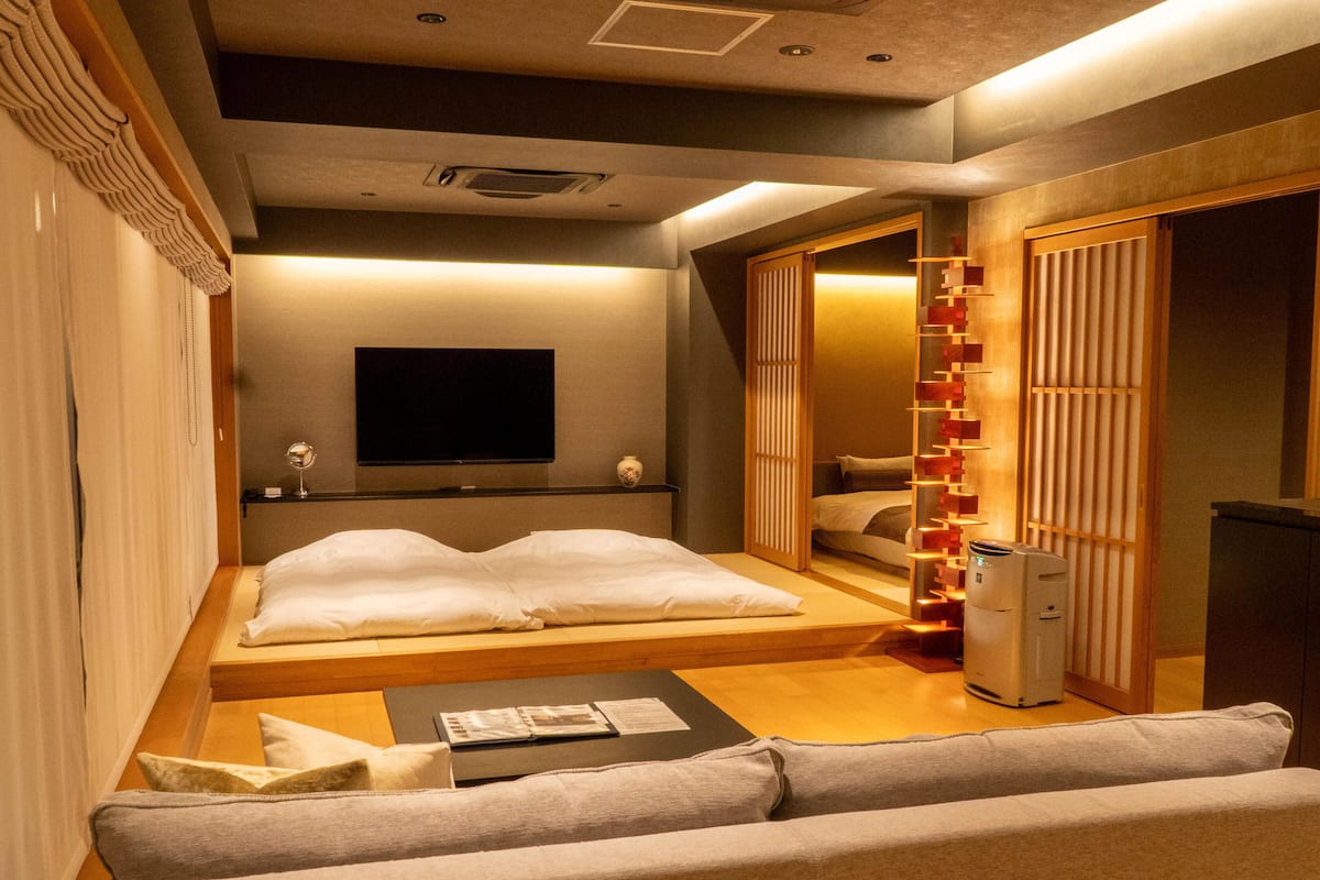 A modern bedroom with a bed, a TV, a sofa, and a cabinet.