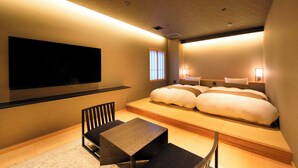 Una habitación de hotel moderna con una cama grande, un televisor de pantalla plana en la pared, una mesita y una zona de estar.