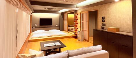 A hotel room with a bed, a TV, a desk, and a kitchenette.