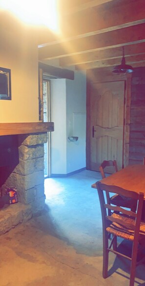 Ein Essbereich mit Kamin aus Stein, einem Holztisch und Stühlen.