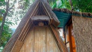 A thatched-roof hut with a wooden door and a small porch area. - Taman Asta Gangga by ecommerceloka (Sidemen)