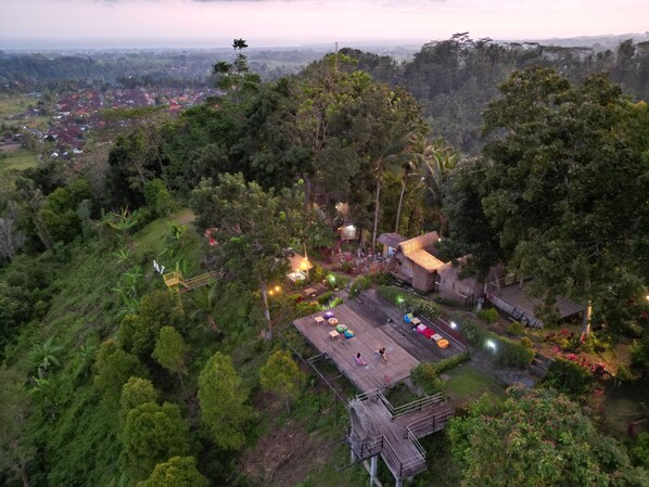 A high-altitude resort with a wooden deck, thatched-roof buildings, and lush greenery.