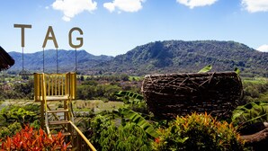 A view of a rural landscape with a wooden chair and a woven basket, with the word "TAG" visible in the background. - Taman Asta Gangga by ecommerceloka (Sidemen)