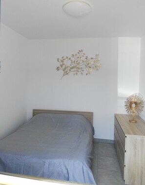 A bedroom with a bed, a dresser, and a wall decoration.