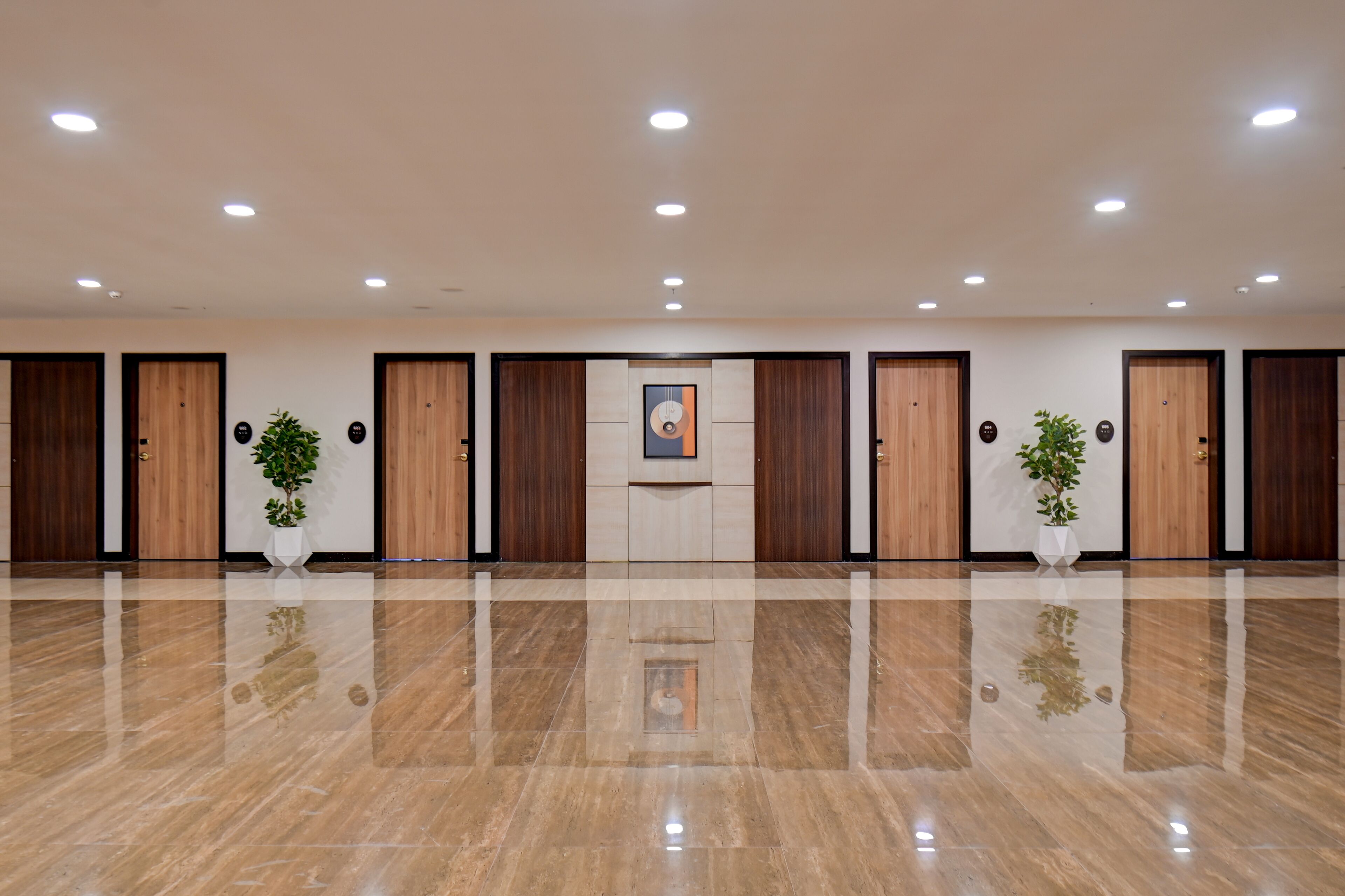 Un'ampia hall con pavimento in marmo lucido, porte in legno e piante in vaso.